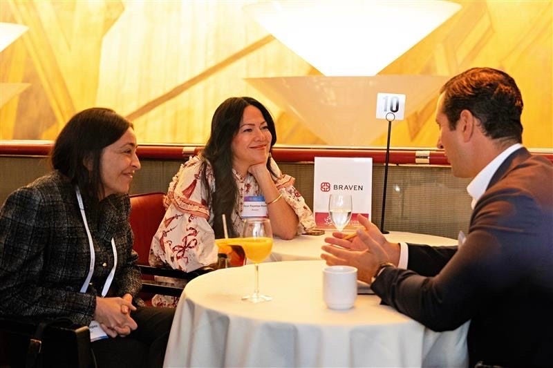 Braven Nonprofit Board Networking at Apollo Three professionals engage in a conversation at a Braven-hosted table during a nonprofit networking event, seated with beverages and a table sign marked “10.”