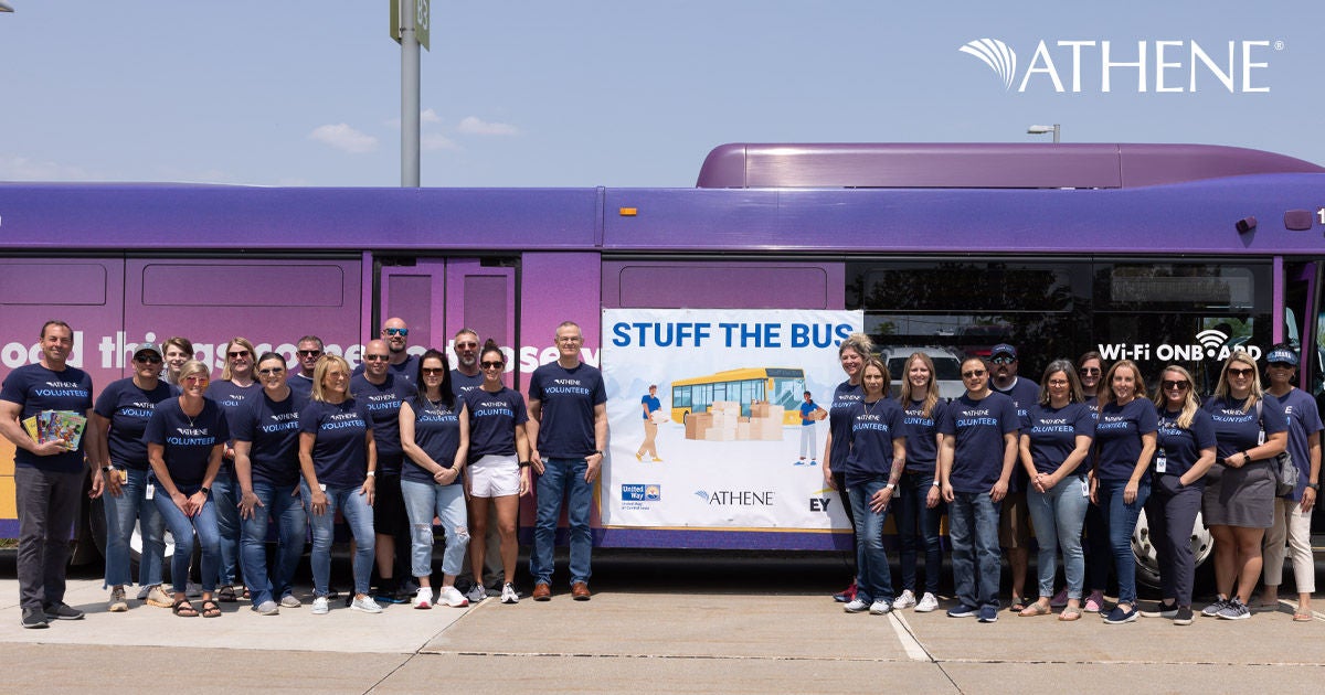 Athene colleagues wearing matching t shirts in front of a bus at a volunteering event 