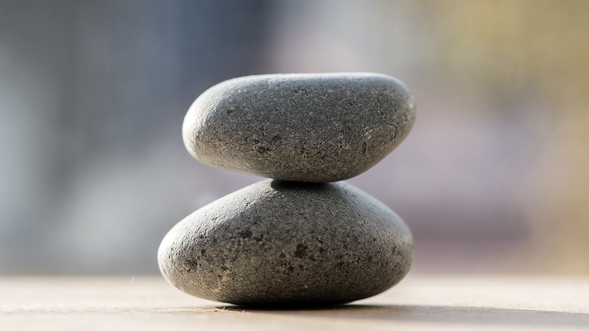 Close‑up of two balanced stones stacked atop each other, symbolizing stable growth and the expertise‑driven equity support Apollo provides to management teams to achieve strategic business outcomes.