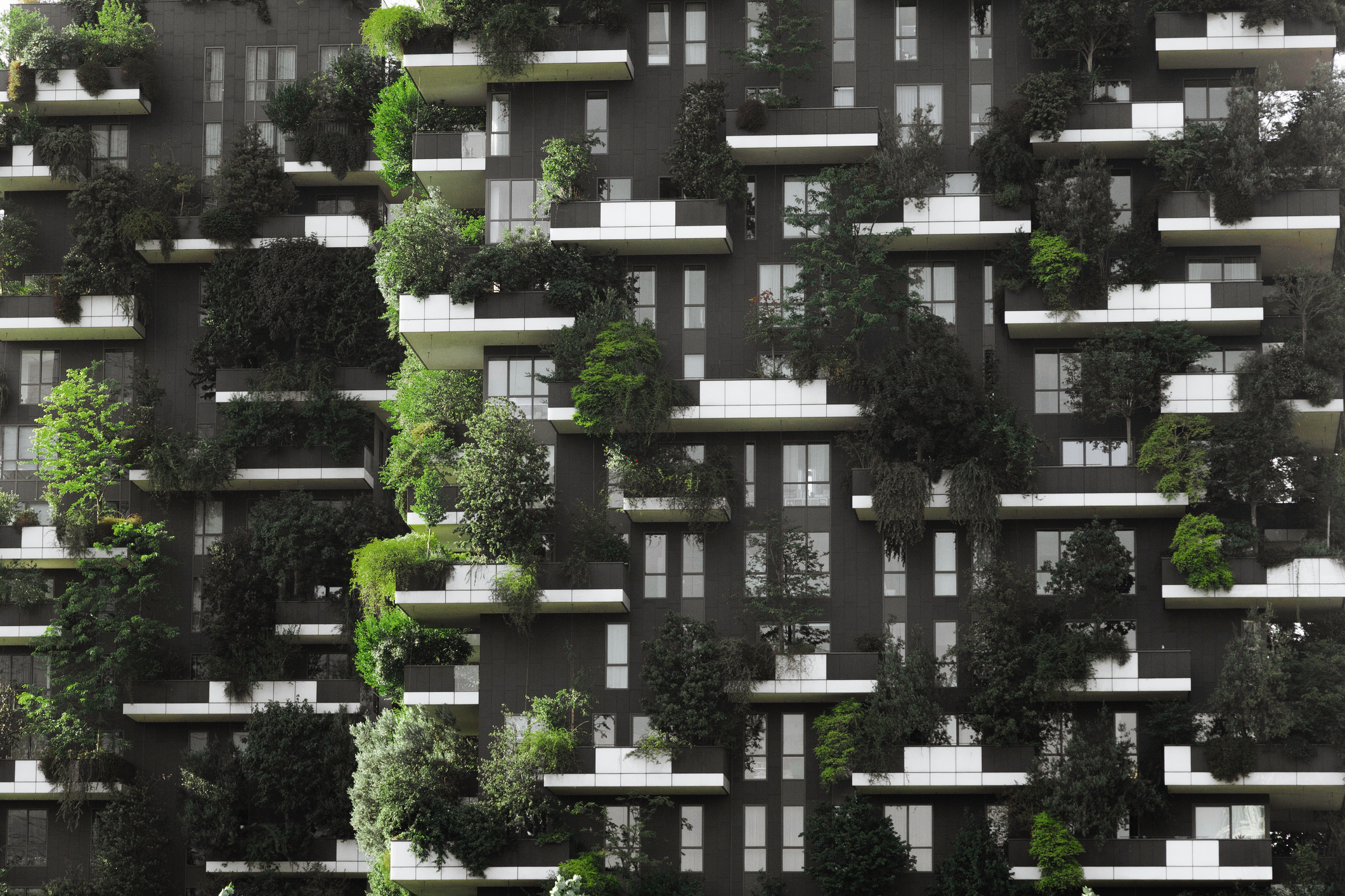 Portfolio Allocations: Where Does Private IG Credit Belong? Modern residential building with layered balconies covered in dense greenery and trees, illustrating sustainable urban design and real assets in private markets, aligned with themes of private credit and long-term asset allocation