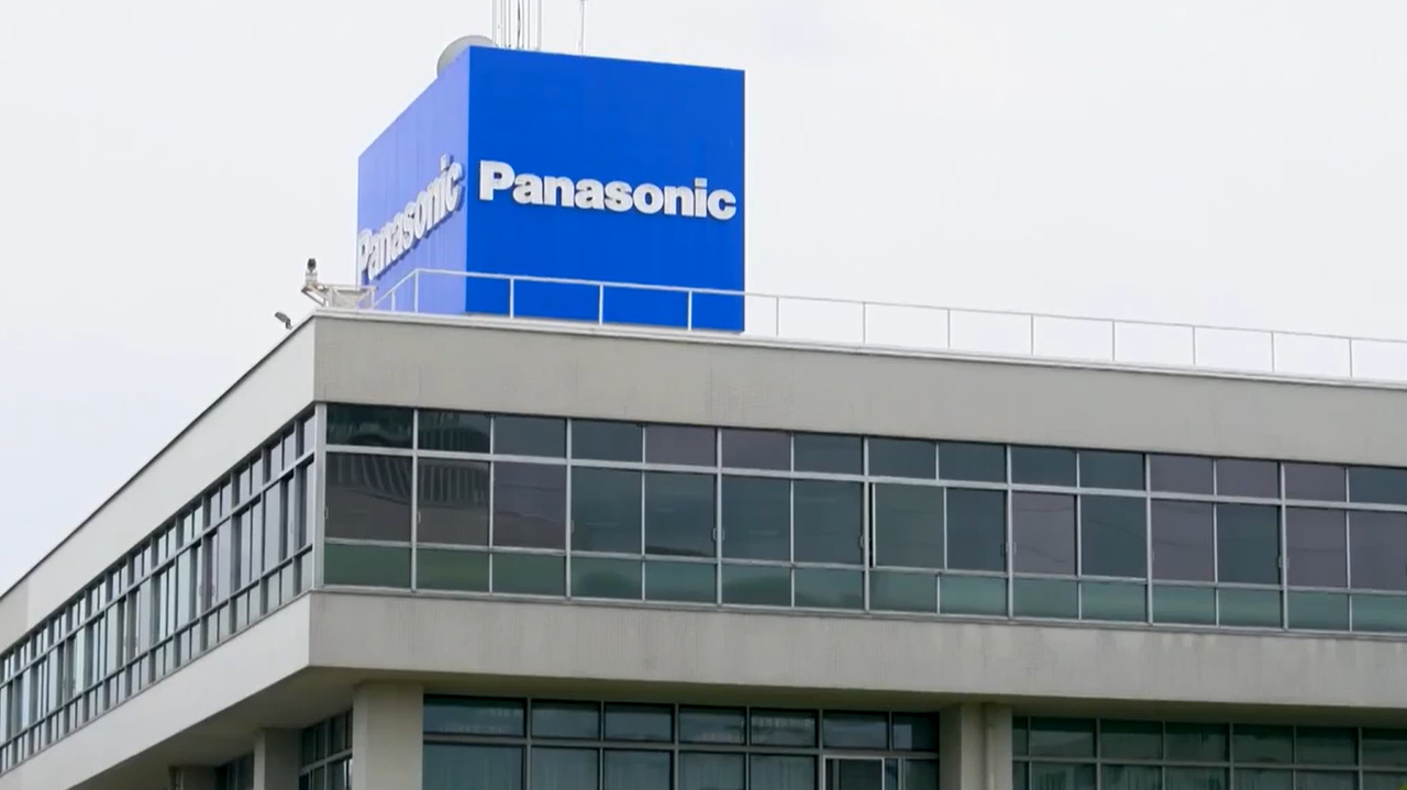 Panasonic Automotive: Partnership in Motion Modern commercial building with glass windows and a large blue Panasonic sign mounted on the rooftop, representing Panasonic Holdings and its automotive systems division